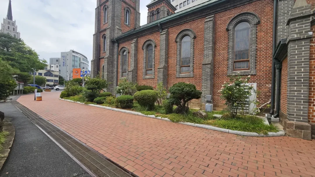 계산성당 옆 붉은 벽돌 산책로와 화단, 멀리 보이는 제일교회 첨탑